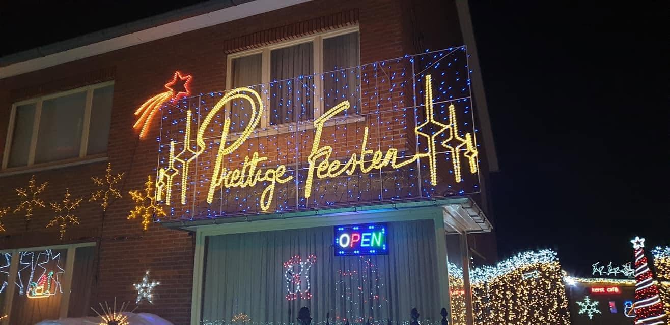 De gevel van Rudy's Kersttuin, versierd met sterren en een lichtgevend bord Prettige Feesten